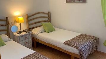A room with two single beds, a nightstand with a lamp, a small table with a mirror, and a map on the wall.