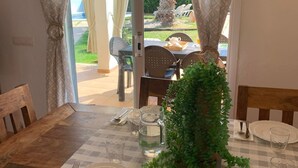 Un comedor con mantel a cuadros, sillas de madera y una planta en maceta.