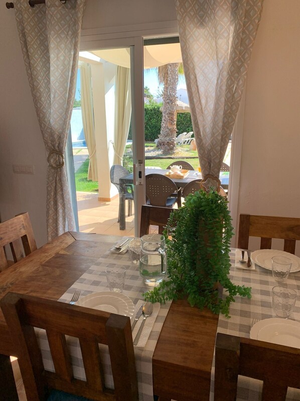 A dining area with a checkered tablecloth, wooden chairs, and a potted plant.