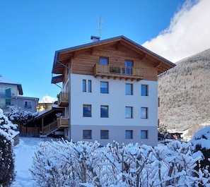 Un immeuble à plusieurs étages, doté d’une façade en bois, de balcons et surplombant un paysage enneigé.