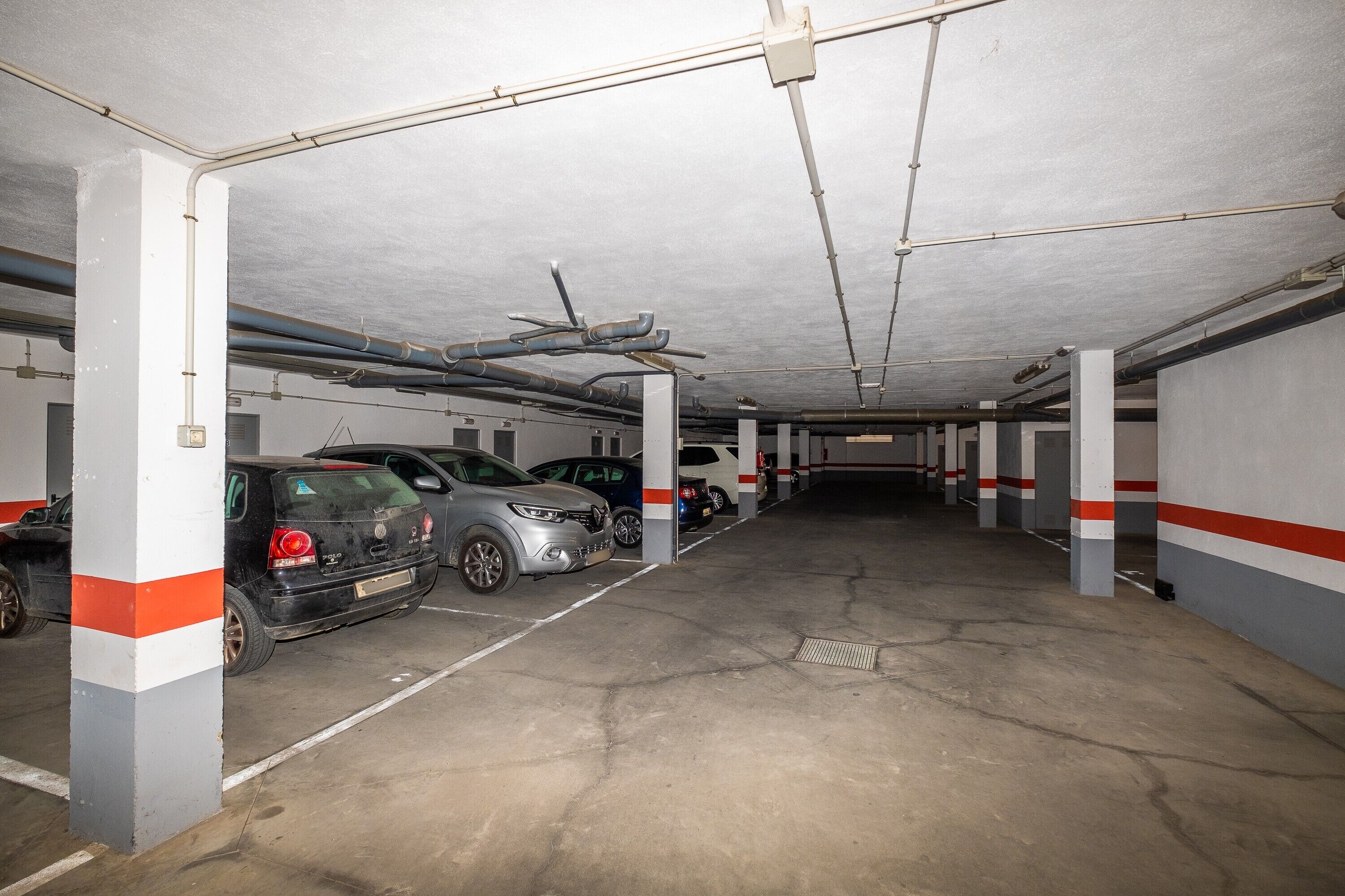 Eine mehrstöckige Parkgarage mit Betonböden und weißen Säulen, auf der mehrere Autos geparkt sind.