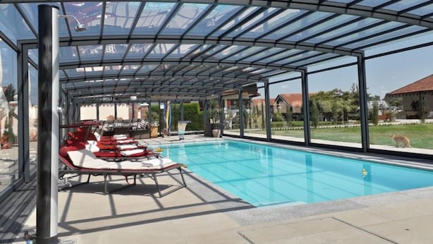 Une piscine intérieure avec des chaises longues et un toit en verre.