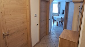 Um corredor com portas de madeira, piso de azulejos e um arco que dá para uma sala de jantar.