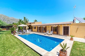 Une piscine avec des chaises longues, un espace patio et une vue sur les montagnes en arrière-plan.
