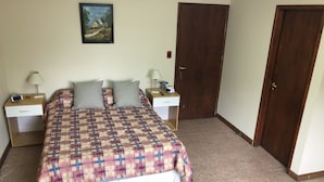 A bedroom with a bed, two nightstands, a painting, and two doors. - A un paso de todo Lo de Richard (Ushuaia)