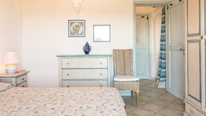 A bedroom with a bed, dresser, chair, and a door leading to another room.