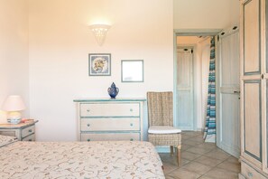Une chambre à coucher comprenant un lit, une commode, une chaise et une porte donnant sur une autre pièce.