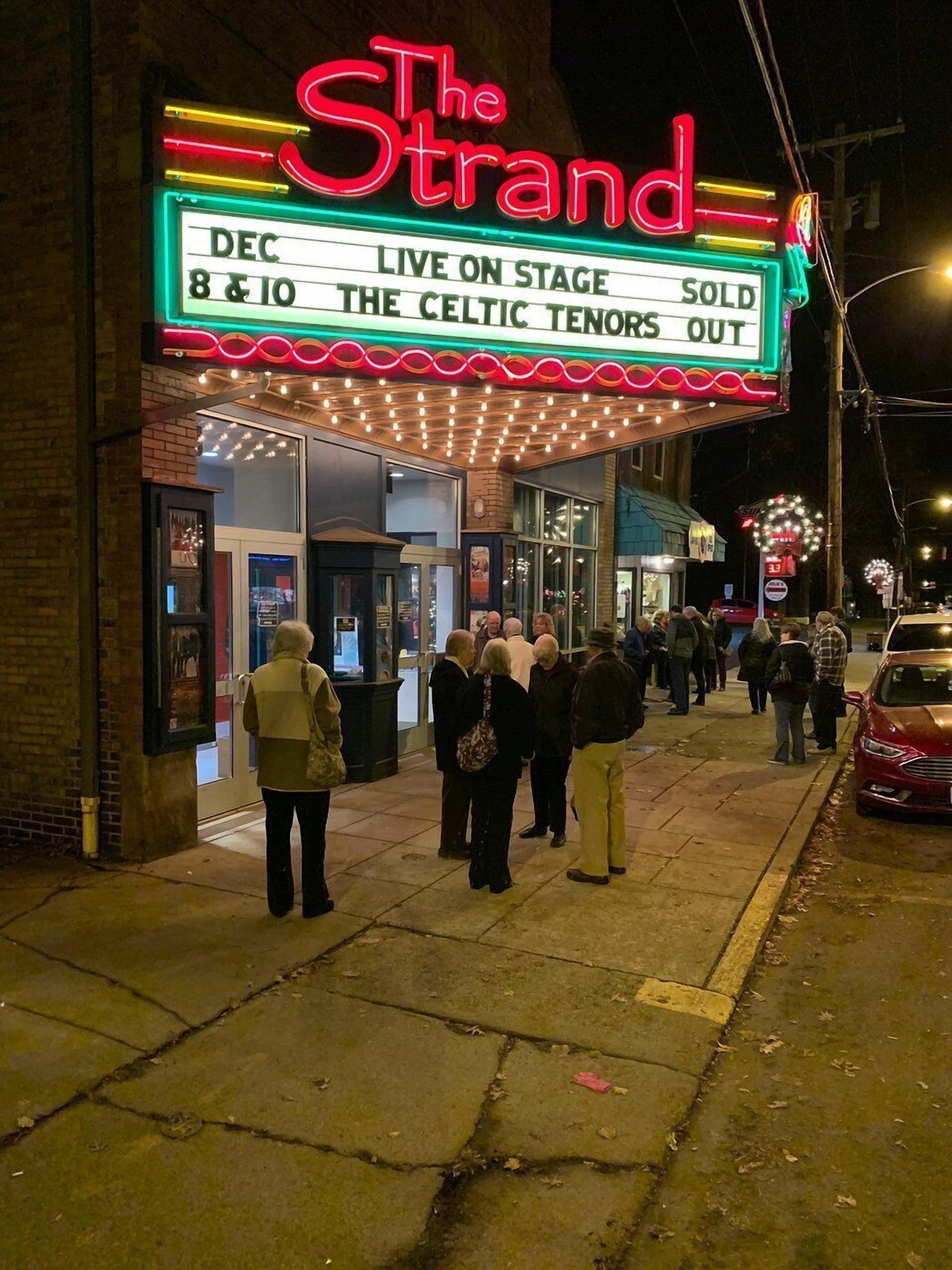 A theater marquee with a neon sign advertising a live performance.