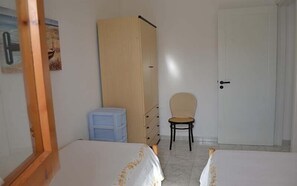 A bedroom with two beds, a wardrobe, a chair, and a door. - Charming Holiday Apartment "Casa a Torre dell'Orso PT55" with Garden (Torre dell'Orso)