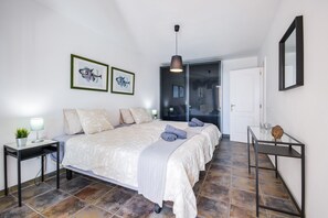 A bedroom with a large bed, a bedside table with a lamp, and two framed pictures on the wall. - Vacation Apartment "Casa Amanecer 3" with Sea & Mountain Views, Pool, and Terrace (Macher)