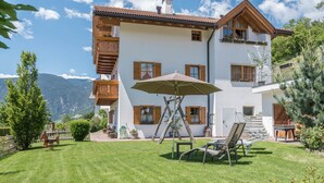 Een huis met twee verdiepingen, een balkon, een gazon en een tafel met stoelen.
