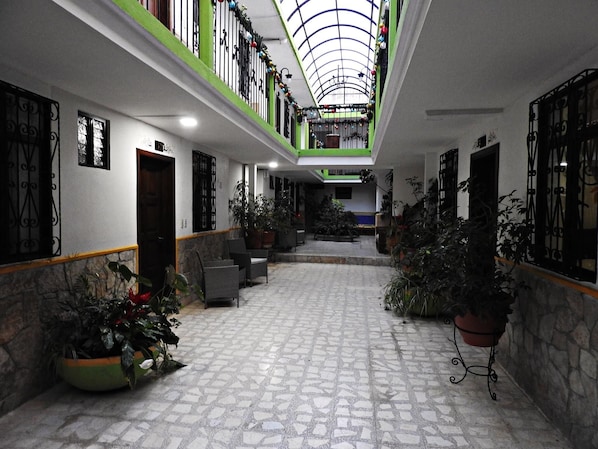 A spacious indoor area with a tiled floor, potted plants, and a high ceiling with a skylight.