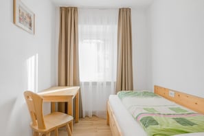 A room with a bed, a wooden desk, and a chair.