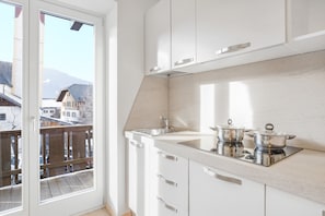 A modern kitchen with white cabinets, a stainless steel sink, and two pots on the countertop.
