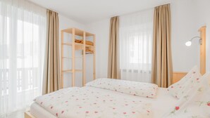 A bedroom with a bed, a wooden shelf, and a bedside table with a lamp.