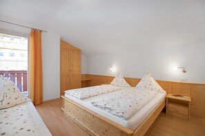 Une chambre à coucher avec un lit en bois, une table de chevet, une armoire et une fenêtre avec des rideaux.