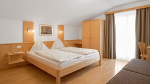 Ein Schlafzimmer mit einem Holzbett, einem Nachttisch, einem Kleiderschrank und einem Fenster mit Vorhängen.
