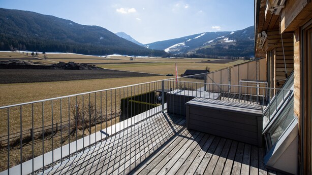Una terraza de madera con vista a un paisaje montañoso.