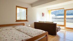 Un dormitorio con cama, sofá, ventana y vistas a un paisaje nevado.