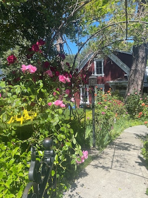 A garden with a pathway, a red house, and a yellow bench. - Cozy Suite Downtown Nevada City Located In The Historic Hatfield House (Nevada City)