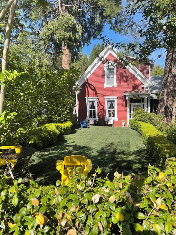 A red house with a white porch, surrounded by greenery and a well-maintained lawn. - Cozy Suite Downtown Nevada City Located In The Historic Hatfield House (Nevada City)