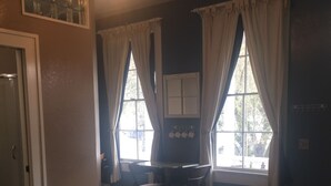 Un dormitorio con una cama, un escritorio y dos ventanas con cortinas.