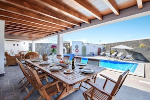 An outdoor dining area with a pool and stone walls.