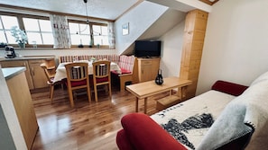 A compact living space with a dining area, a TV, and a cozy seating area.