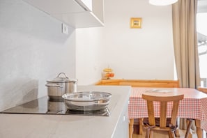 Keittiössä on liesi, kattila ja paistinpannu työtasolla.