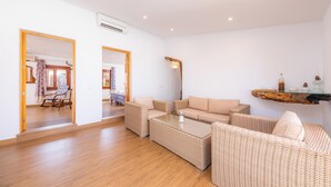 Ein modernes Wohnzimmer mit Korbmöbeln, einem Glastisch und Holzboden.