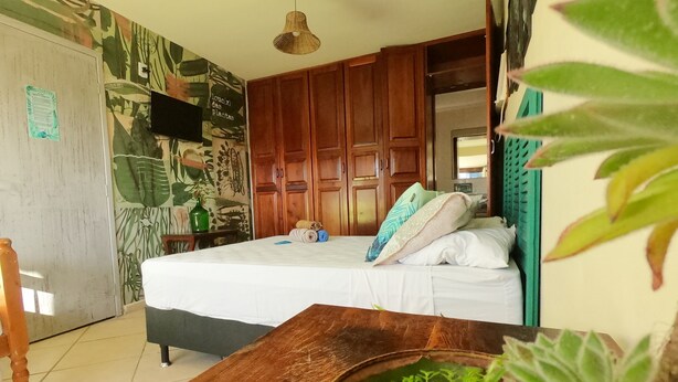 Un dormitorio con cama, armario de madera y una planta verde sobre la mesa.