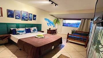 Habitación de hotel con cama, escritorio, silla, ventana con vistas y decoración en la pared.