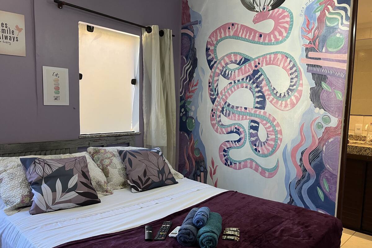 A bedroom with a bed, pillows, a blanket, and a wall tapestry.