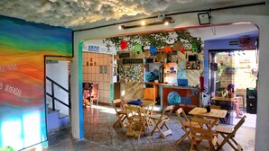 Interior de un hostal con un mural colorido, muebles de madera y un ambiente acogedor.
