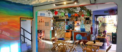 A hostel interior with a colorful mural, wooden furniture, and a cozy atmosphere.