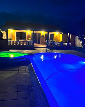Un área de piscina con jacuzzi y zona de estar cubierta.