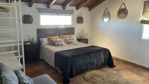 Un dormitorio con cama, mesita de noche, cómoda, ventana y espejo.