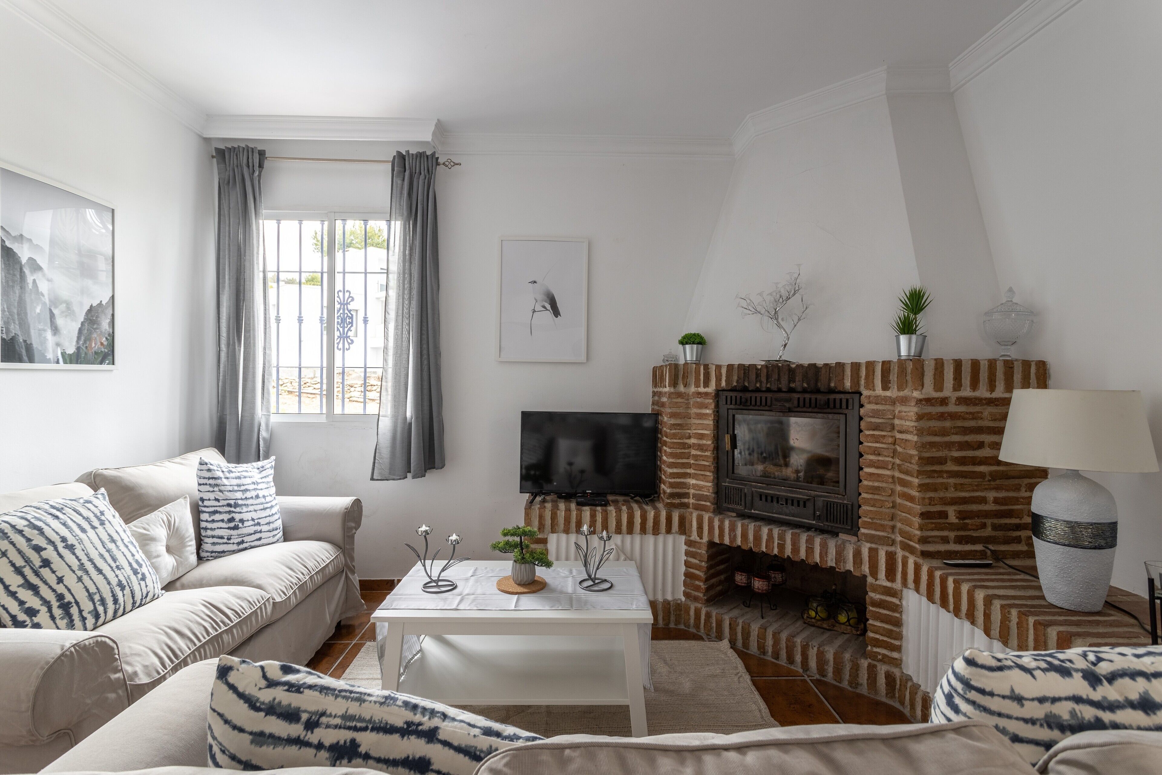 Ein Wohnzimmer mit Sofa, Couchtisch, Kamin, Fernseher und Kunstwerken.