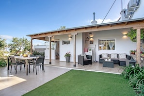Un espace patio comprenant une table et des chaises pour les repas, un canapé et un petit coin cuisine.
