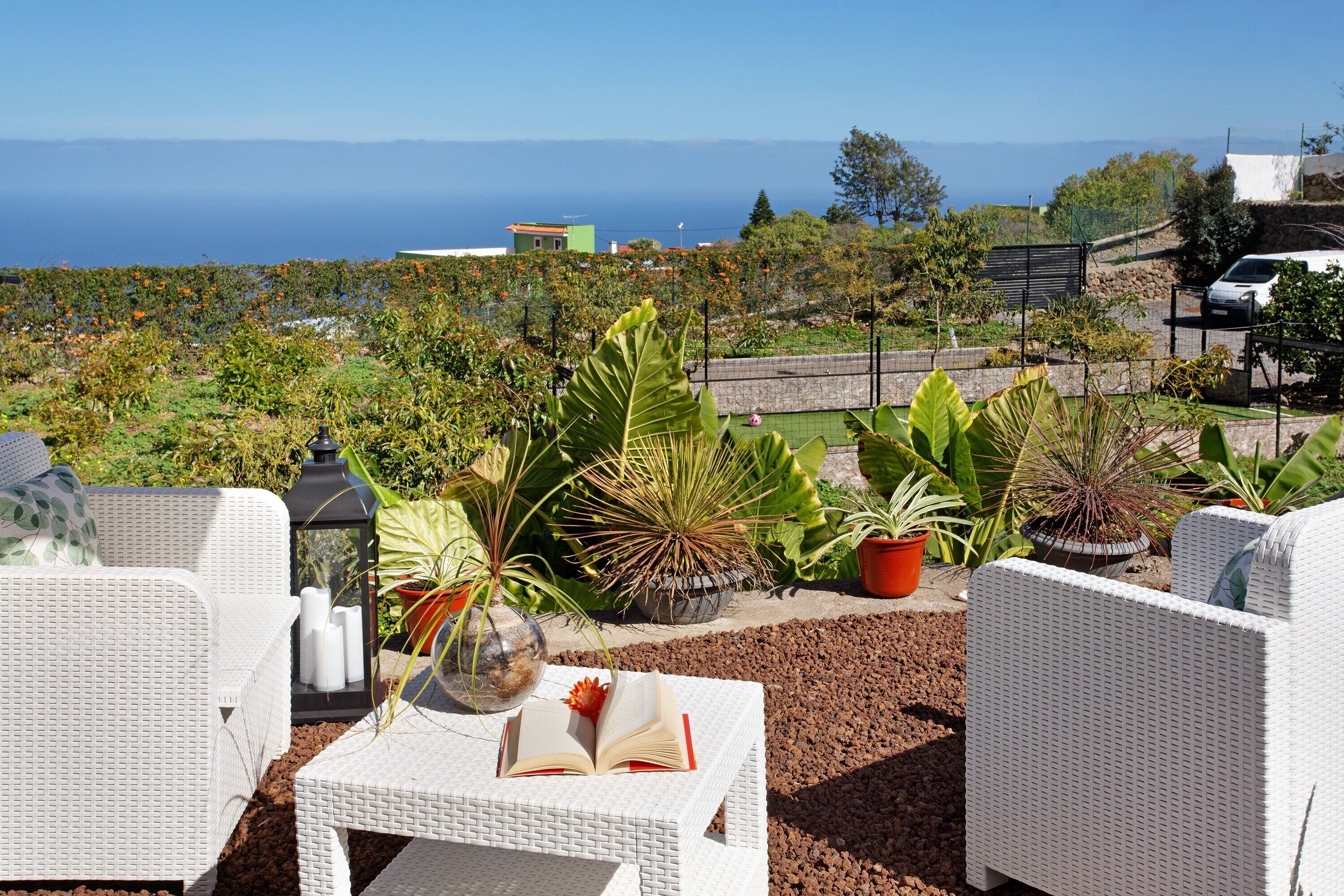 A terrace with wicker furniture, a book, and potted plants.