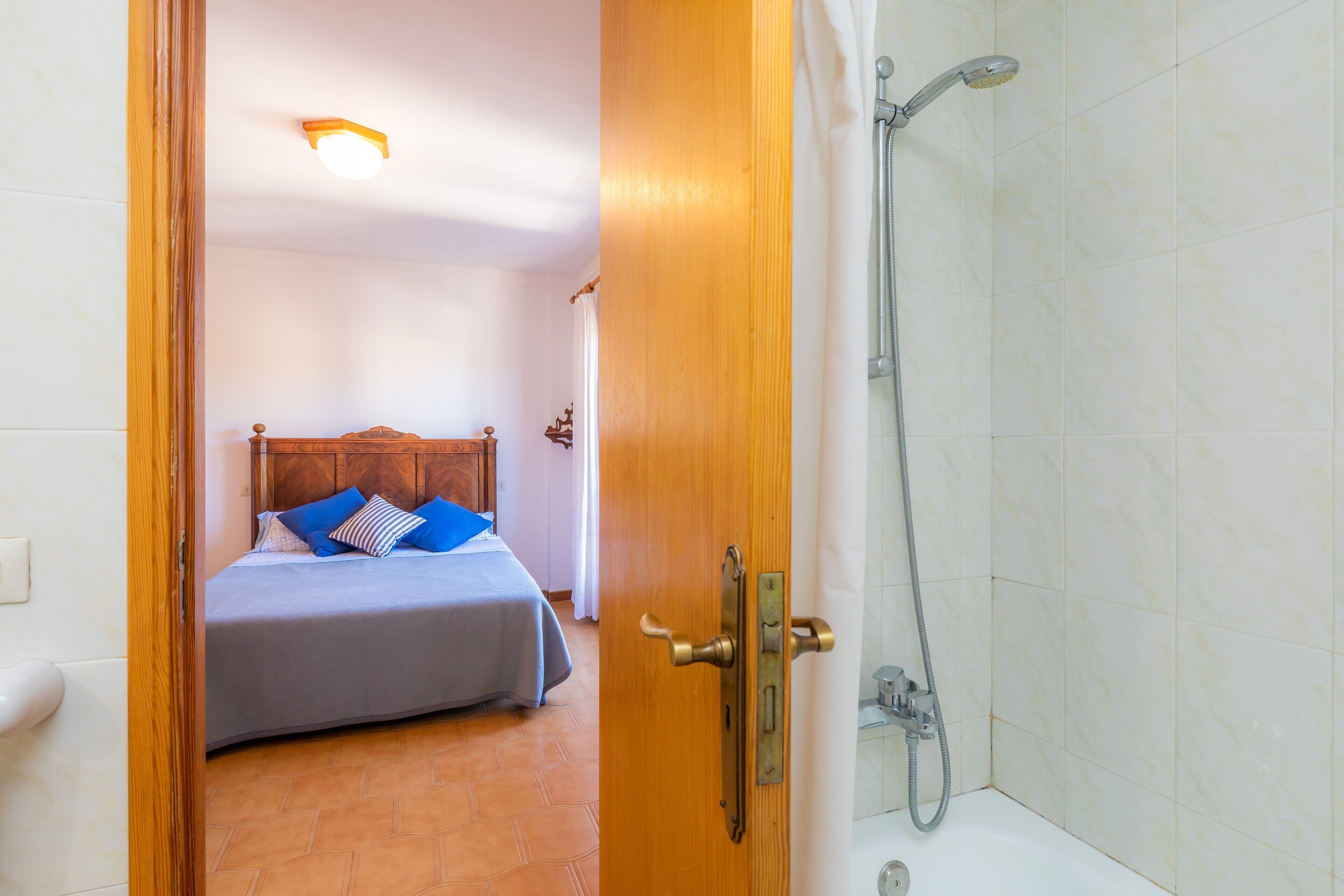 A room with a bed, a wooden door, and a shower area.