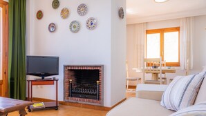 A living room with a TV, fireplace, sofa, and dining area. -  Central Apartment at the Beach Promenade with Wi-Fi and Sea View (Cala Millor)