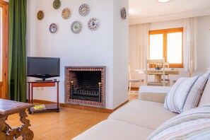Una sala de estar con televisión, chimenea, sofá y comedor.