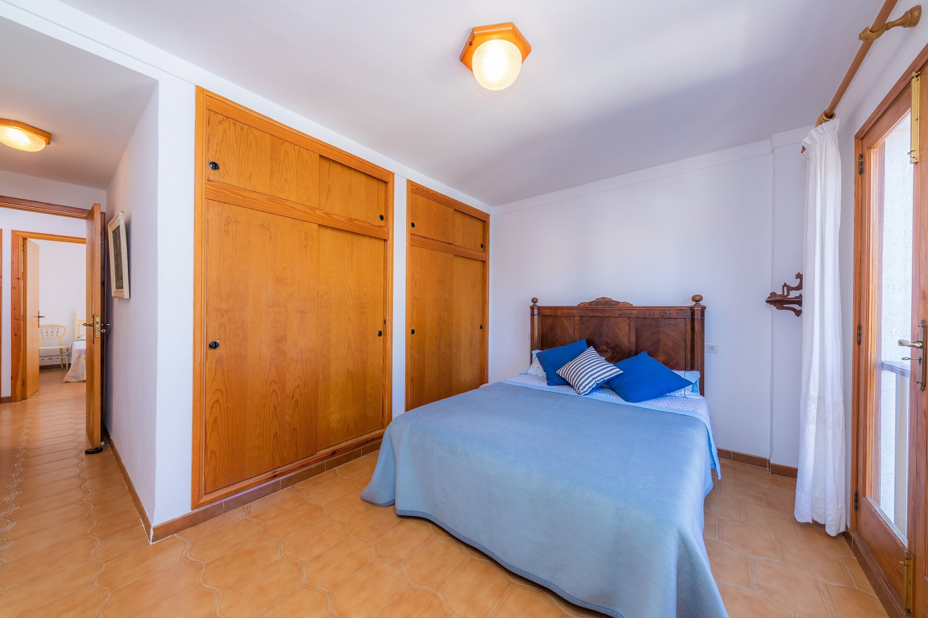 Un dormitorio con cama, armario de madera y lámpara en el techo.