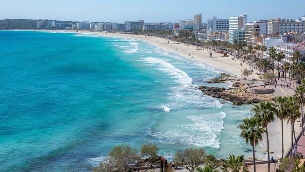 A coastal cityscape with a beach, palm trees, and high-rise buildings. -  Central Apartment at the Beach Promenade with Wi-Fi and Sea View (Cala Millor)