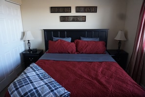 A bedroom with a bed, two nightstands, a bench, and wall decorations.