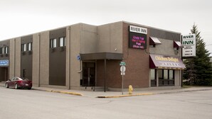 A building with a sign for River Inn, featuring a digital menu board, a sign for Chicken Delight and Pizza, and a sign for off-sale ice cold beer.