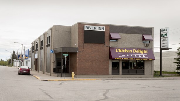 A building with a sign for 'River Inn' and a restaurant named 'Chicken Delight and Pizza' on the ground floor.