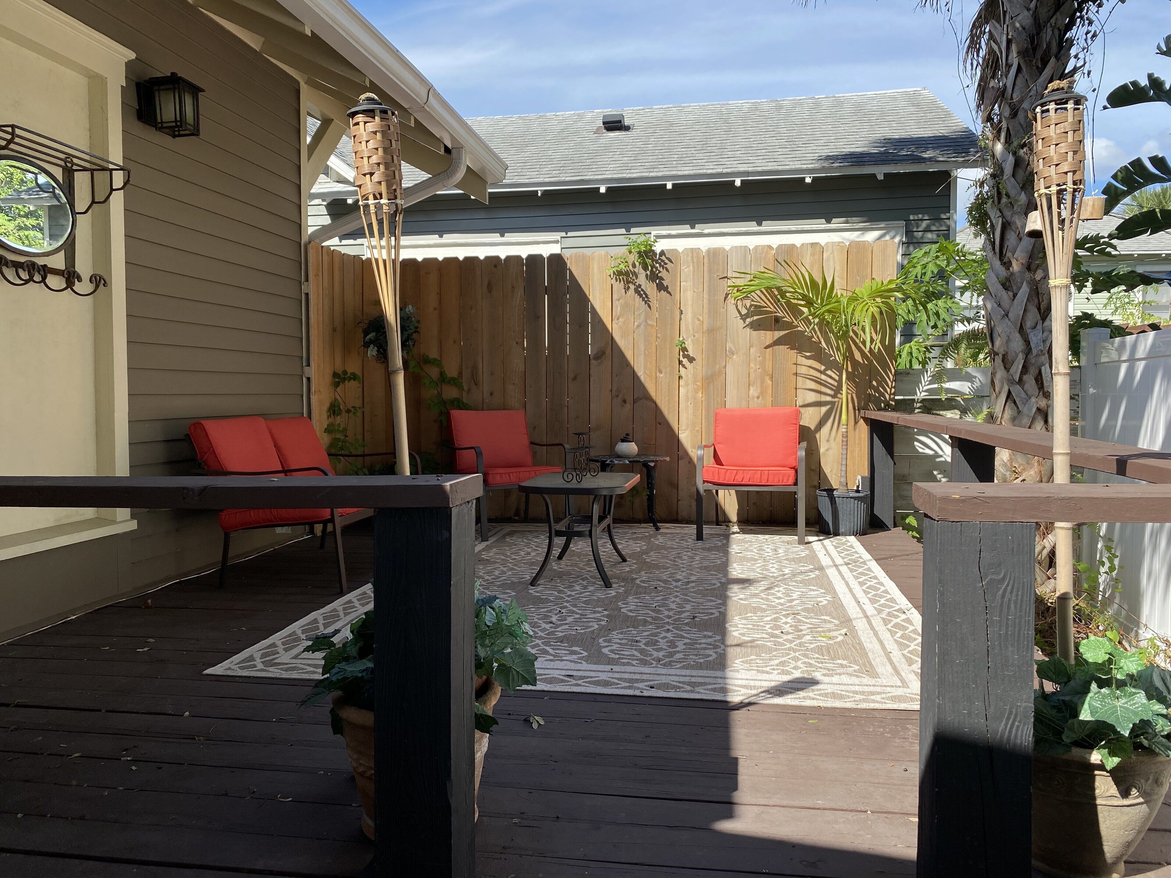 A wooden deck with outdoor furniture, a pergola, and potted plants.