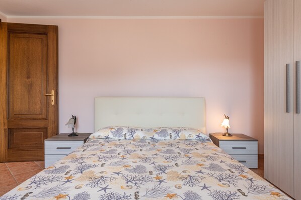 Une chambre à coucher avec un lit, des tables de chevet, une lampe, une porte en bois et une armoire.